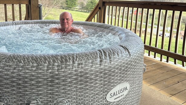 Un bain à remous portant l’inscription « SALUSPA HONOLULU », installé sur une terrasse en bois et offrant une vue sur un paysage.
