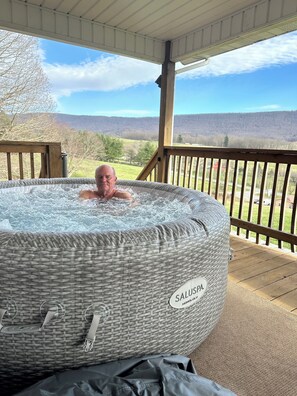 Un jacuzzi con la etiqueta 'SALUSPA HONOLULU' en una terraza de madera, con vistas a un paisaje.
