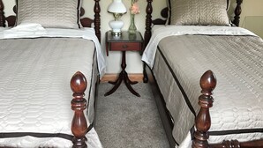 Deux lits doubles avec des têtes de lit en bois, une petite table de chevet avec une lampe et un vase avec des fleurs.