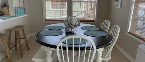 Un comedor con una mesa redonda, sillas blancas y una ventana con persianas.
