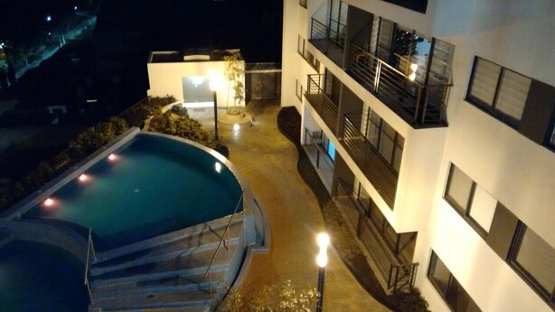 Una piscina con escalones de acceso, rodeada por un edificio con balcones y ventanas.