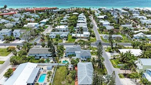 Vue aérienne d’une zone résidentielle côtière, avec des maisons, des routes et une plage.