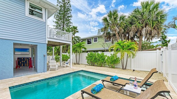 Un jardin avec une piscine, des chaises longues et un patio couvert.