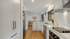 Una cocina moderna con armarios blancos, horno integrado y extractor de acero inoxidable.
