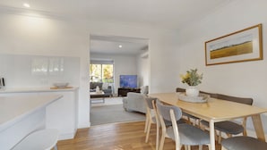 Una sala de estar moderna con comedor, cocina y televisor.