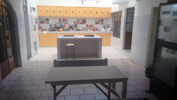 A compact kitchen with a central island, a dining table, and a refrigerator.