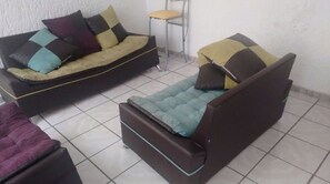 Ein Zimmer mit einer Couch, einem Sessel und einem kleinen Tisch.