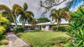 A residential property with a well-maintained lawn, a wooden pathway, and a house with a satellite dish.