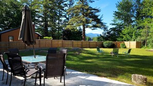 An outdoor patio with a pool, chairs, and a wooden fence.