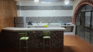 Una cocina con una isla central, dos sillas, un refrigerador y un lavabo.