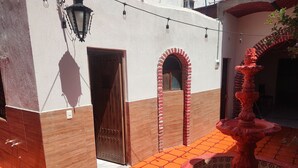 Un patio con suelo de baldosas, una puerta de madera y una fuente.