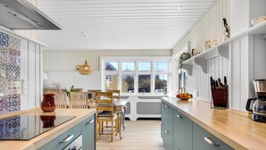 Una cocina moderna con una isla central, sillas de madera y una mesa de comedor.