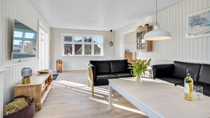 Una sala de estar moderna con un sofá de cuero negro, una mesa de centro blanca y un gran ventanal que proporciona luz natural.