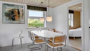 A modern dining area with a white table and chairs, a large abstract painting, and a view of greenery outside. - 3 bedroom pet friendly home in Hejls (Hejls)
