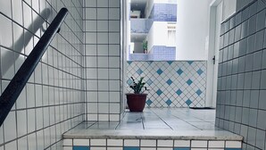 A staircase with white and blue tiles, a potted plant, and a view of a building with blue and white tiles in the background. - Stay here! Stay here! 2/4 furnished apartment in Costa Azul :-) (salvador)