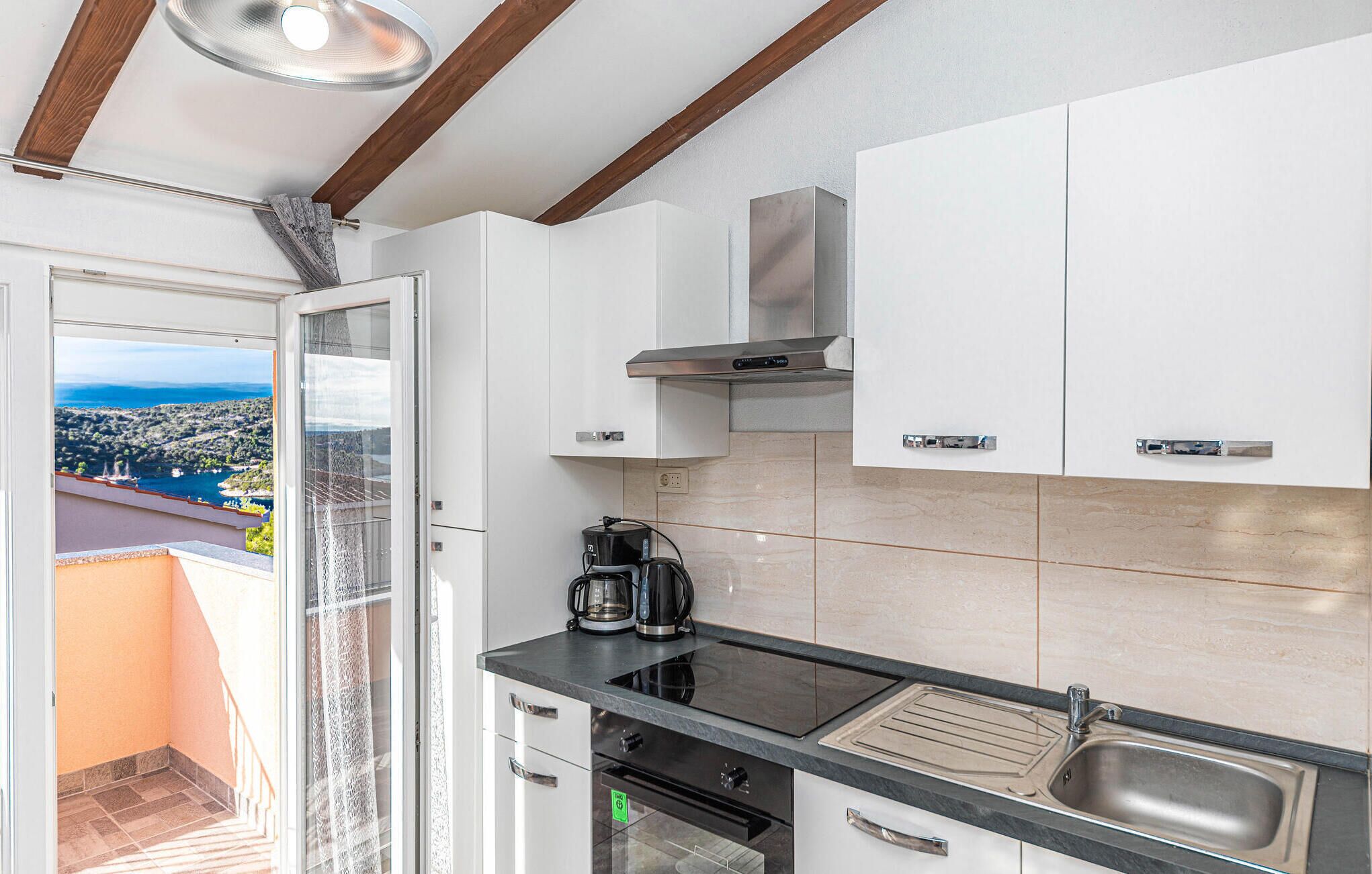 A modern kitchen with white cabinets, a black countertop, and a stainless steel sink.