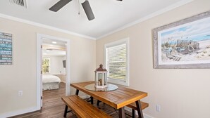 A dining area with a wooden table and benches, a lantern, and a beach-themed painting on the wall. - Pet Friendly House three minute walk to Beach! (Panama City Beach)