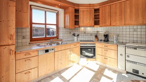 Una cocina con armarios de madera, un ventanal, lavavajillas y cafetera.