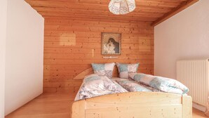 Una cama de madera en una habitación con paredes y lámpara en el techo de madera.