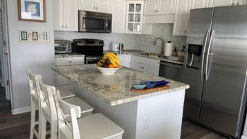 A modern kitchen with white cabinets, stainless steel appliances, and a granite countertop.