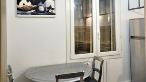 A dining area with a round table, four chairs, and a modern pendant light. - T2 Liberté 3 minutes from beaches, shops and train station (Saint-Raphaël)