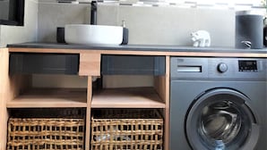A compact laundry area with a washing machine, a sink, and a mirror above it. There are wicker baskets below the counter. - T2 Liberté 3 minutes from beaches, shops and train station (Saint-Raphaël)