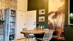 Una sala da pranzo con un tavolo rotondo, sedie in vimini, un tappeto decorato e un grande murale.