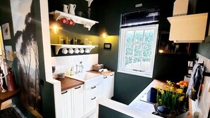 Una cucina compatta con mobili bianchi, una finestra e un piccolo piano di lavoro.