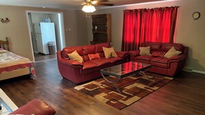 A living room with a red leather sofa set, a glass coffee table, and a wooden floor.