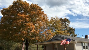 A small house with a porch, an American flag, and a picnic table.