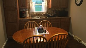 A kitchen with wooden cabinets, a sink, a microwave, and a dining table with chairs.