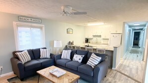 Un salon avec un canapé, une table basse et une cuisine en arrière-plan.