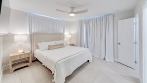 A bedroom with a bed, nightstands, a ceiling fan, and curtains. - NEW REMODEL Steps from private beach access! 4 BR Family Friendly CLEAN  (Fort Myers Beach)