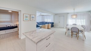 A modern living space with a dining area, a sofa, and a ceiling fan. - NEW REMODEL Steps from private beach access! 4 BR Family Friendly CLEAN  (Fort Myers Beach)