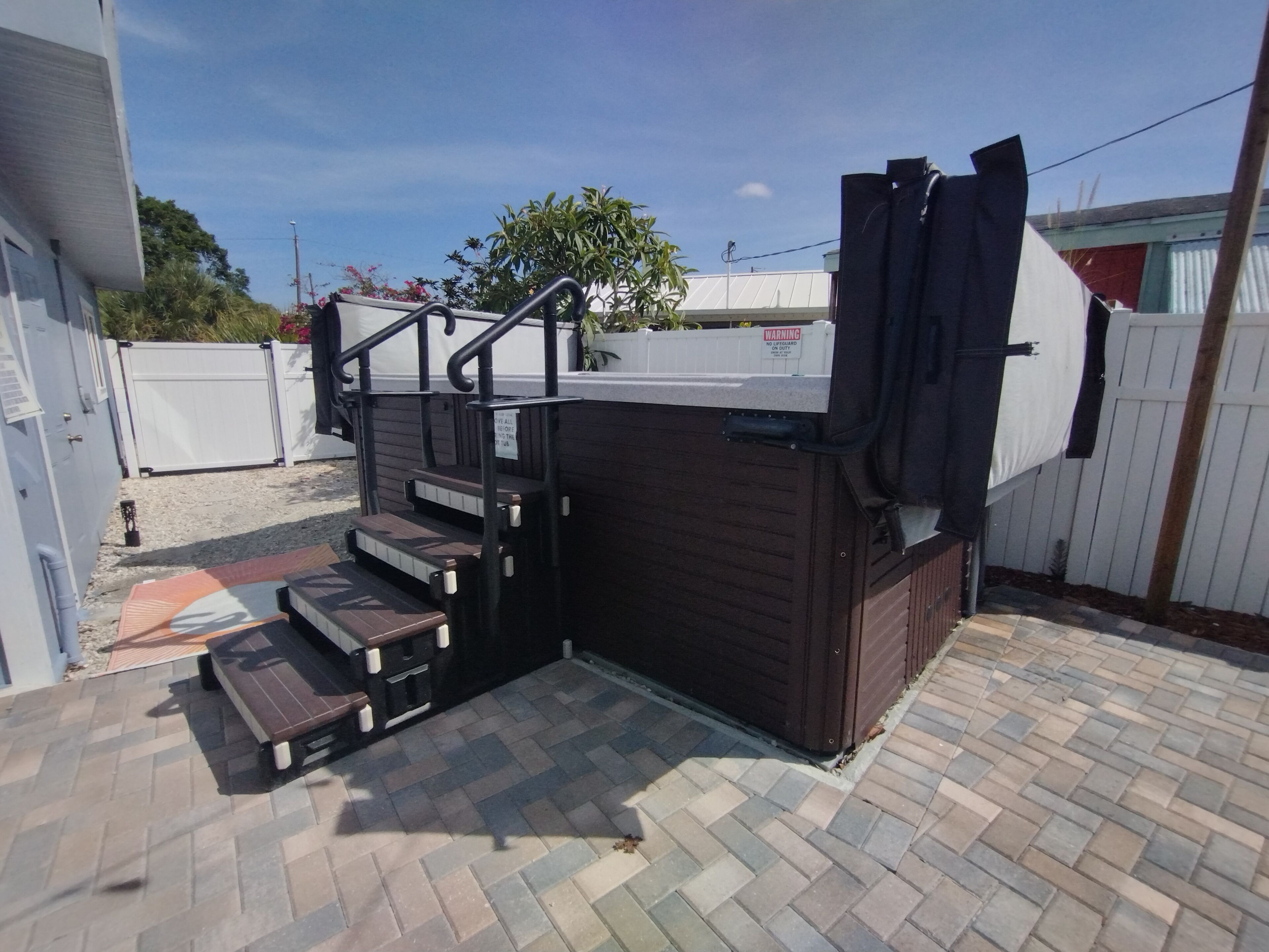 A patio area with a wooden bench, a set of stairs, and a small outdoor kitchen area.