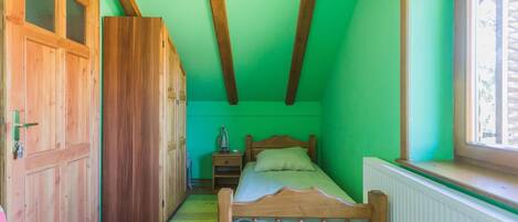 Un dormitorio con una cama de madera, una mesita de noche, una pared verde y una ventana.