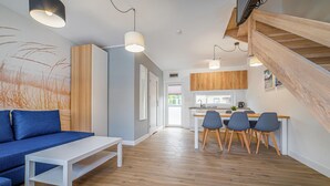 Una sala de estar moderna con un sofá azul, una mesa de centro blanca y un comedor de madera con cuatro sillas.