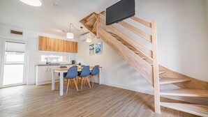 Una cocina moderna con armarios de madera, un comedor con mesa y sillas, y una escalera de madera.