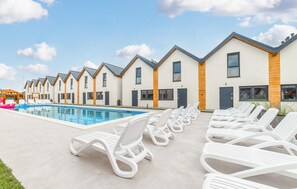 A row of modern, single-story buildings with a swimming pool and lounge chairs in front. - Cozy home in Rewal with heated swimming pool (Rewal)