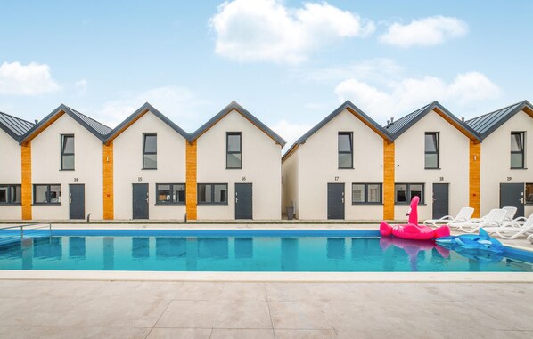 A row of modern, numbered hotel rooms with a swimming pool in the foreground. - Cozy home in Rewal with heated swimming pool (Rewal)