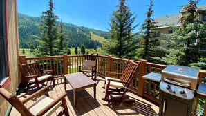 Une terrasse en bois avec des meubles d’extérieur, un barbecue et une vue imprenable sur les montagnes.