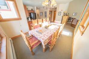 A dining area with a large table, wooden chairs, and a chandelier. - Red Hawk Townhomes 2342 (Keystone)