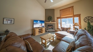 Un salon avec une cheminée, un téléviseur et un ventilateur de plafond.