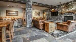 A rustic interior with stone walls, leather furniture, and a fireplace. - Black Bear 8074 (Keystone)