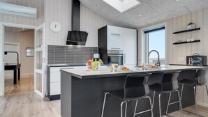 Una cocina moderna con una isla central, taburetes de bar y vistas al exterior.