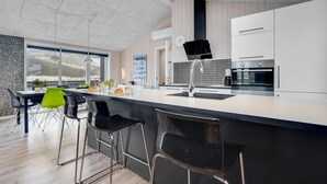 Una cocina moderna con una isla grande, taburetes de bar y vistas al exterior.
