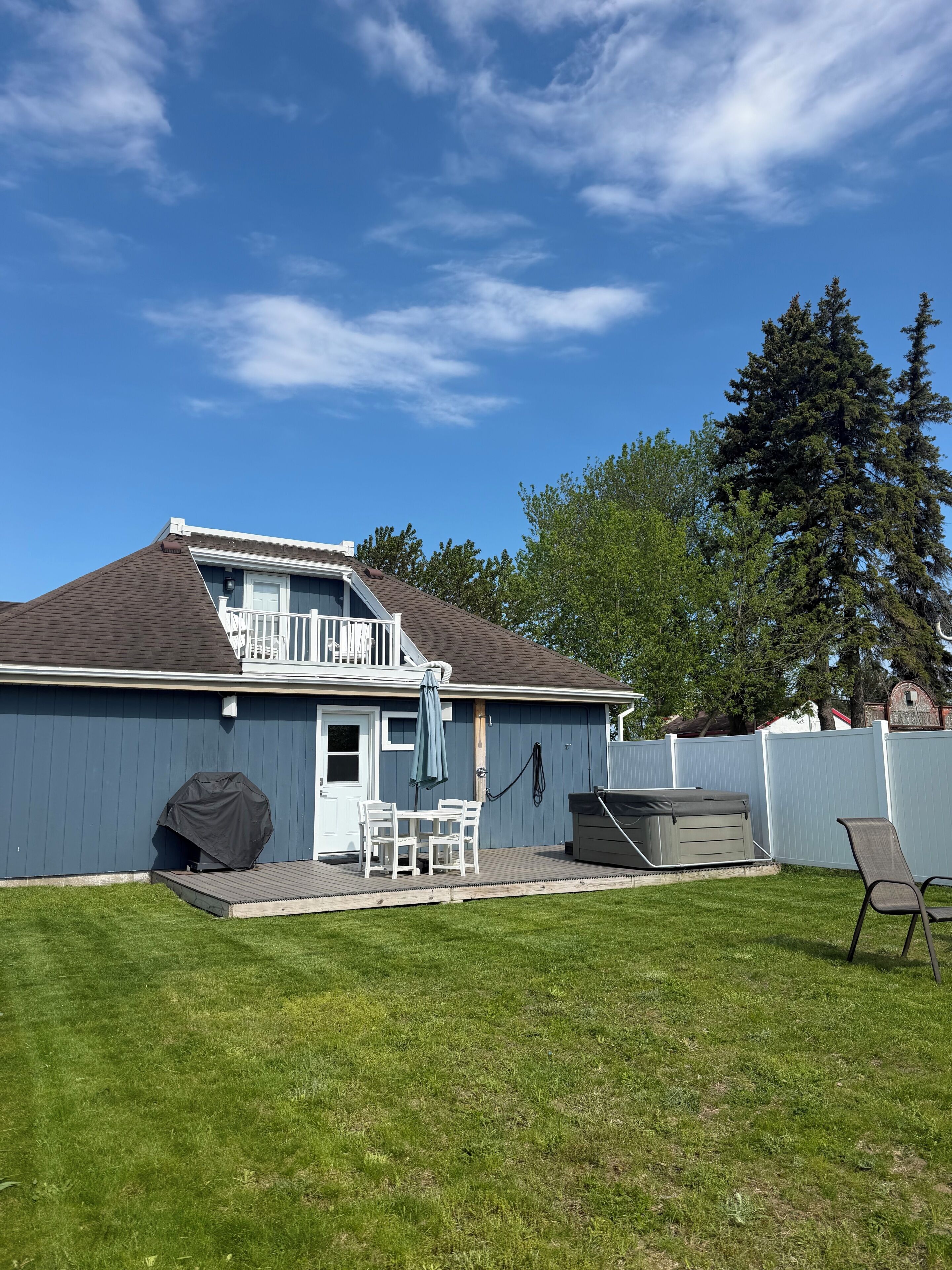 Une maison avec une terrasse, un barbecue couvert et un jacuzzi.