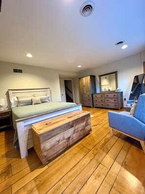 A bedroom with a bed, wooden bench, dresser, and chair.