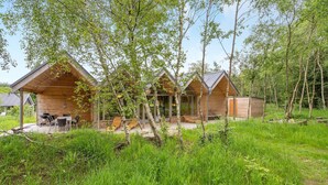 A cabin complex with three wooden cabins, each featuring a porch and outdoor seating. - 3 bedroom gorgeous home in Silkeborg (Silkeborg)