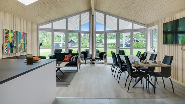 Une pièce spacieuse et bien éclairée, avec un plafond haut, de grandes fenêtres et un coin cuisine moderne.